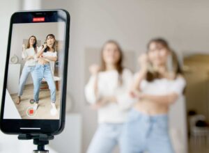 woman in white sleeveless shirt and blue denim skirt holding black smartphone